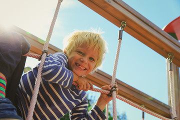 little boy playing on monkey bars at playground