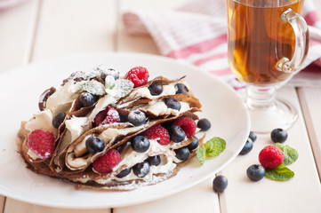 Pancakes with blueberries and raspberries, mascarpone cream and tea