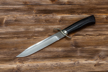 Hunting steel knife handmade on a wooden background, close-up