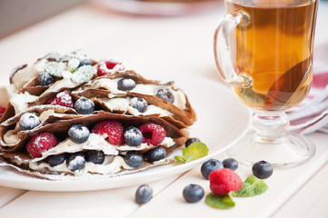 Pancakes with blueberries and raspberries, mascarpone cream and tea