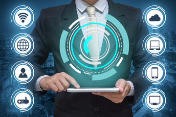 Businessman holding tablet PC and wireless communication network on city background