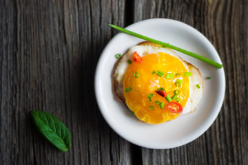 Fried Egg on White Plate. Top View Food on Dark Wooden Background.