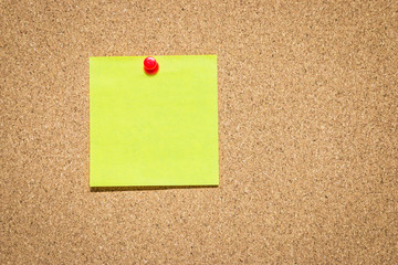Yellow reminder sticky note on cork board, empty space for text