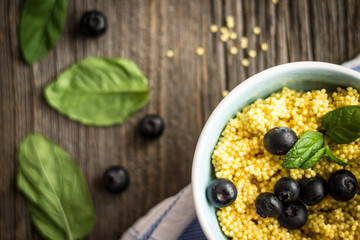 Top View Puree of Millet Grains with Blueberries and Raw Ingredients on Wooden Background.