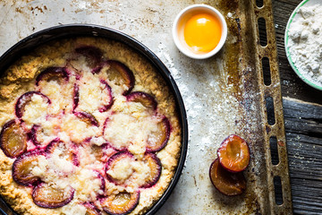 Plum Cake with Raw Cooking Ingredients on Wooden Kitchen Table