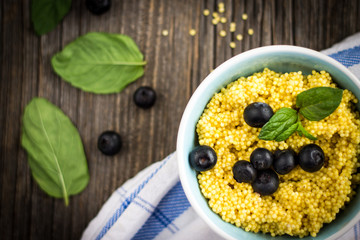 Puree of Millet Grains with Blueberries and Raw Ingredients on Wooden Background.