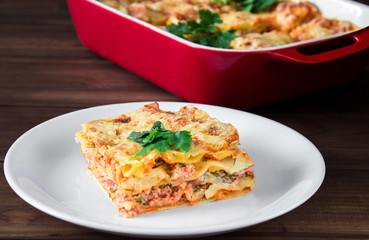 Close-up of a traditional lasagna topped with parskey leafs served on a white plate