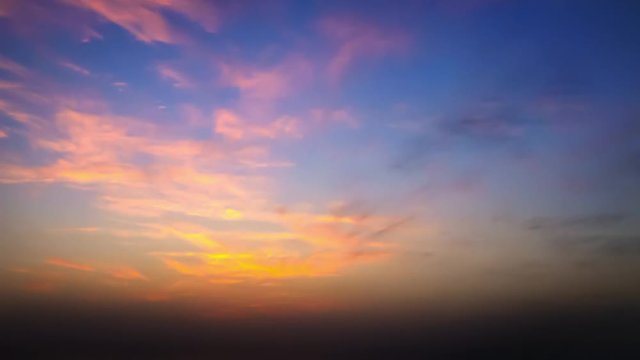 time lapse of clouds crossing the amazing sky over the sea or ocean at sunset. transition from day to night. The clouds cross slowly from left to right colored yellow orange purple blue.