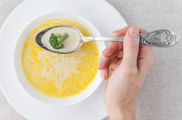 cheese soup with broccoli in a white plate on a white linen tablecloth