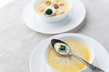 cheese soup with broccoli in a white plate on a white linen tablecloth