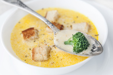 cheese soup with broccoli in a white plate on a white linen tablecloth