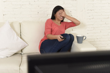 Naklejka premium latin woman sitting at home sofa couch in living room watching television scary horror movie