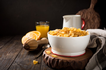 Corn flakes with milk on dark wooden background. Copy space. Helthy breakfast concept.