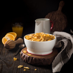 Corn flakes with milk on dark wooden background. Copy space. Helthy breakfast concept.