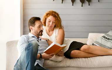 Lovely couple reading book together at home