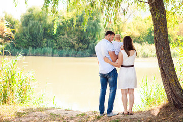 Fototapeta premium Happy young family spending time outdoor on a summer day, picnic in the park.