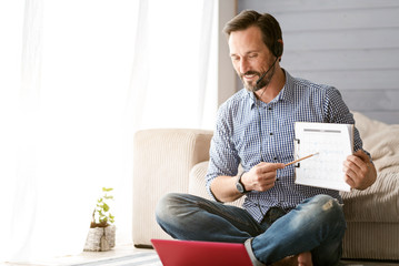 Involved bearded man using modern gadgets at home