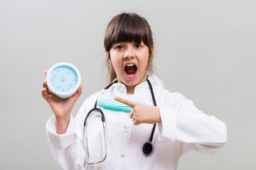 Little doctor is showing that is time to think about health by pointing at clock.