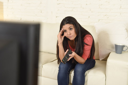 young beautiful hispanic woman at home watching television tired and bored