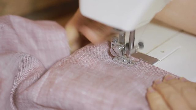 sewing on the sewing machine, closeup. woman's hand seamstress
