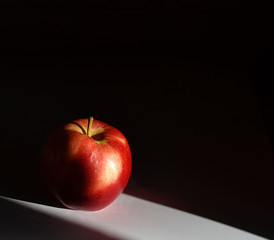 red Apple on a white table on a black background