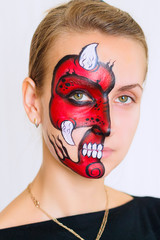 Woman face with painted devil mask on it isolated on white background