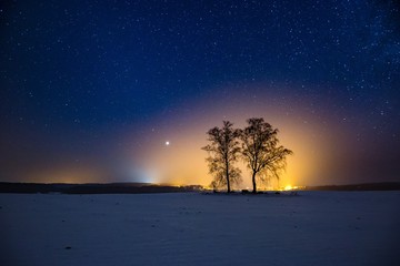 Fototapeta na wymiar Milky way and starry sky over winter landscape and distant village