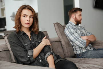 Obraz premium Sad quarrel loving couple sitting on sofa indoors