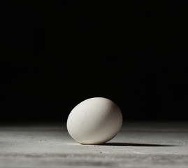 white chicken egg on a white table on a black background