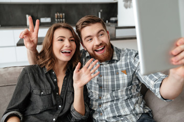 Happy loving couple talking with friends by tablet computer.