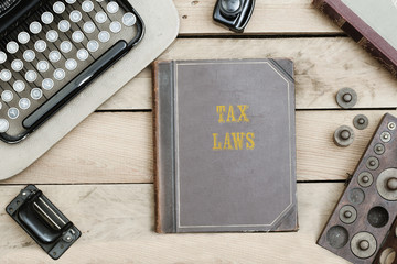 Tax Laws on old book cover at office desk with vintage items © MichaelJBerlin