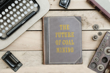 Future of Coal Mining, on old book cover at office desk with vintage items © MichaelJBerlin