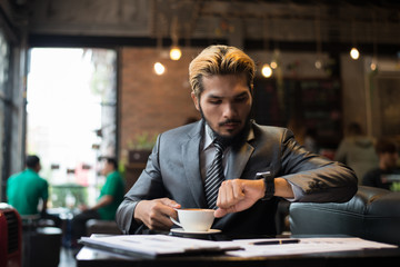 Fototapeta premium Business man looking at his watch while working at cafe.