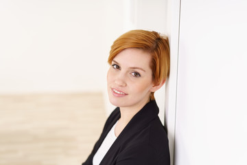 schöne junge frau lehnt an einer weißen wand