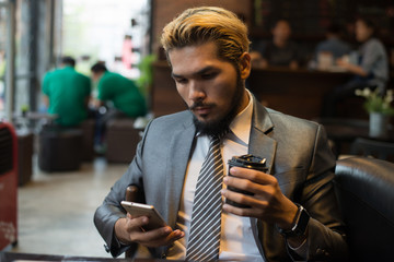Businessman sitting at cafe With Coffee Using Mobile Phone.