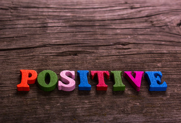 Positive word made from colored wooden letters on an old table. Concept