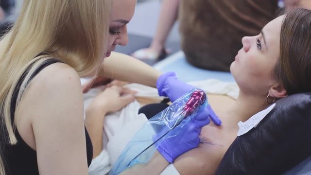 the process of tattoo master girl makes a print on the chest