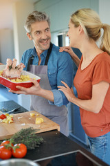 Middle-aged couple having fun cooking together in home kitchen