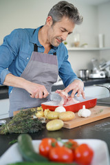 Mature man in kitchen cooking dish for dinner