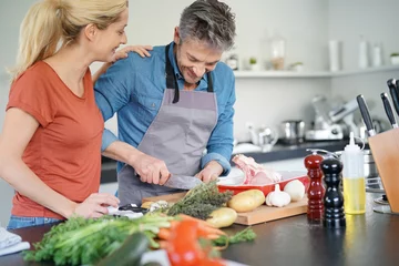 Deurstickers Koken Paar van middelbare leeftijd met plezier samen koken in de keuken thuis