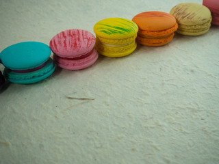 Close up row of sweet and colorful french macaroons or  macarons on rough white paper, Dessert for St valentine day. Selective focus.