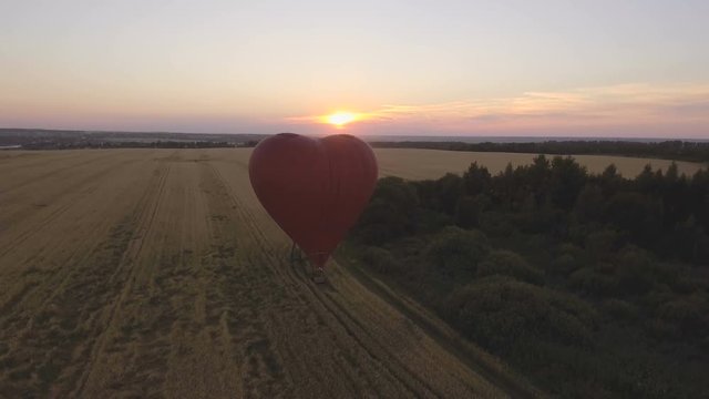 Red balloon in the shape of a wheat heart.Aerial view:Hot air balloon in the sky over a field countryside in the beautiful sky and sunset. 4K video,ultra HD.