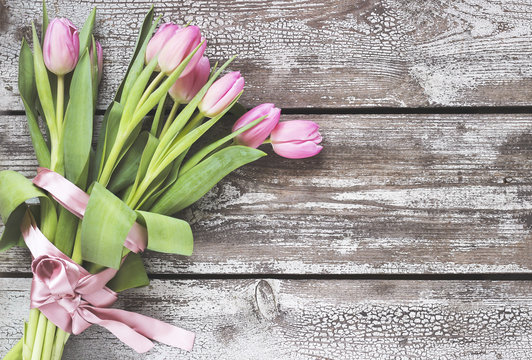 Bouquet of pink tulips on a shabby wooden table.