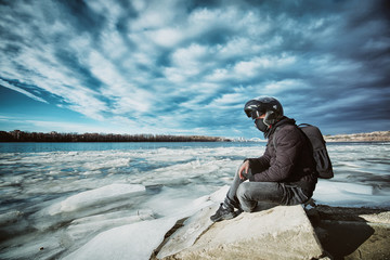 A young motorcycle enthusiast enjoying a beautiful view of a frozen river after his first winter...