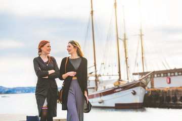 Two beautiful girls walking at Oslo harbour - obrazy, fototapety, plakaty