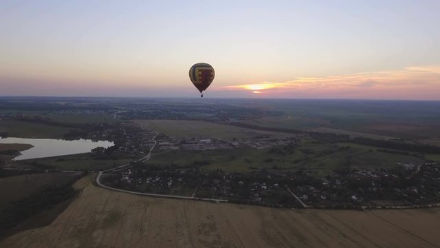 Hot air balloon in the sky over wheat field in the countryside.Aerial view:Hot air balloon in the sky over a field countryside the beautiful sky and sunset.Aerostat fly the countryside. 4K video,ultra