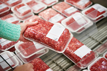 Buyer woman chooses chopped meat in shop