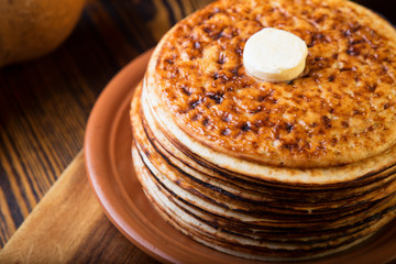 Stack of thick pancakes with butter on a plate