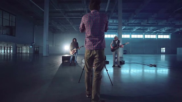 A director aiming with the camera to the band performing a song while video making. Camera movement around