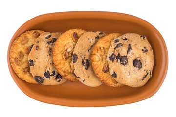 Cookies with peanuts and chocolate in a brown plate. Isolated on white background.
